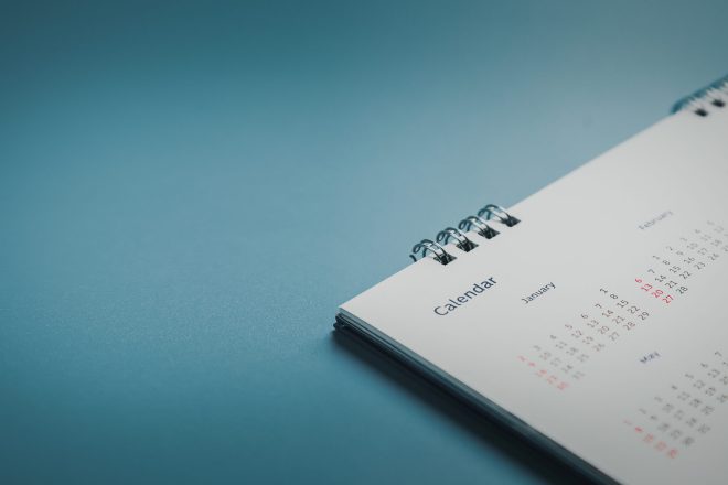 Embroidered red pins on a calendar event Planner calendar,clock to set timetable organize schedule,planning for business meeting or travel planning concept.